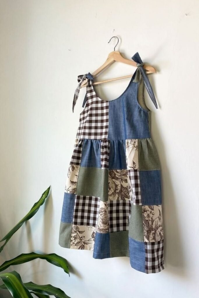 Patchwork sundress made from denim, gingham and floral fabric squares on a hanger