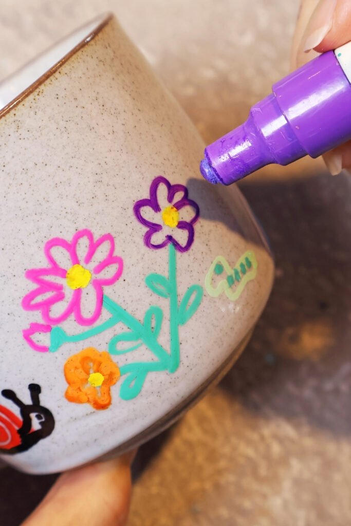 Paint pen drawing colorful flowers on a ceramic mug