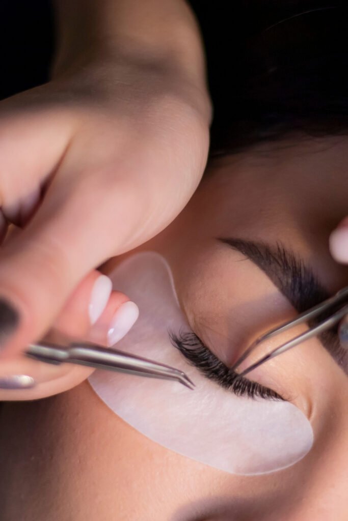 Lash technician applying eyelash extensions with tweezers