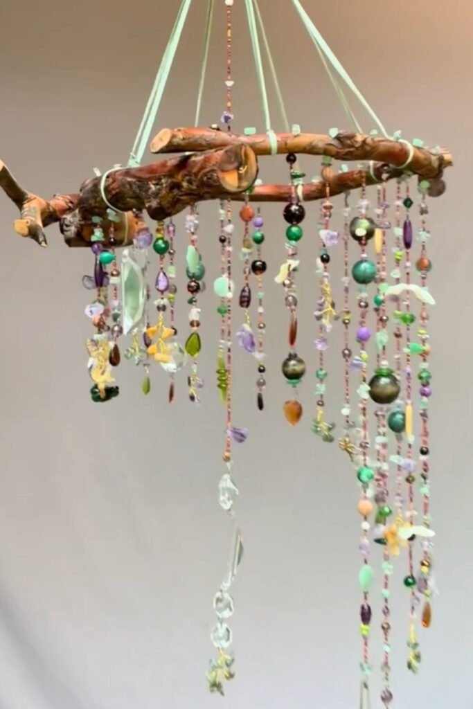 Driftwood wind chime with long strands of colorful glass and wooden beads