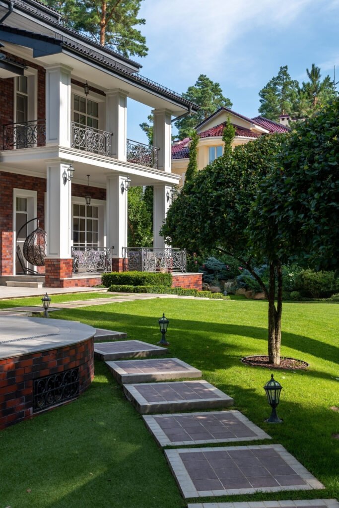 Winding stone pathway through a green lawn to a cottage-style house