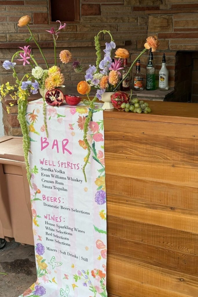 Hand-painted watercolor bar menu sign surrounded by wildflowers