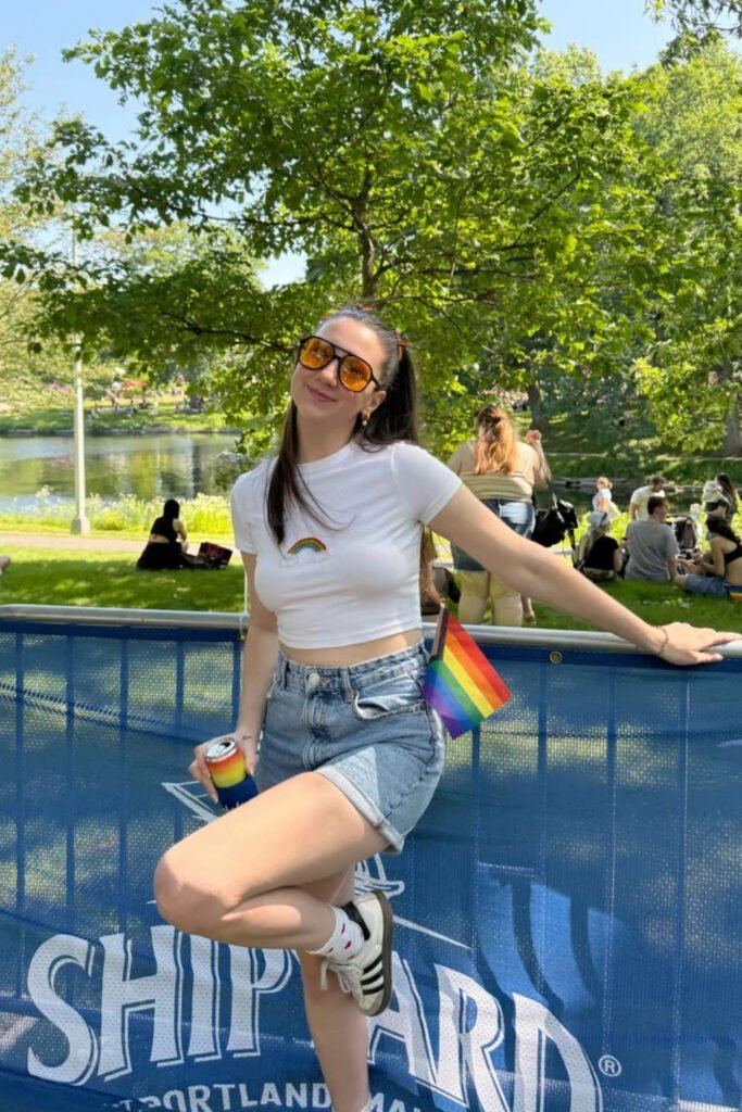 White tee and denim shorts with a small Pride flag on a sunny day
