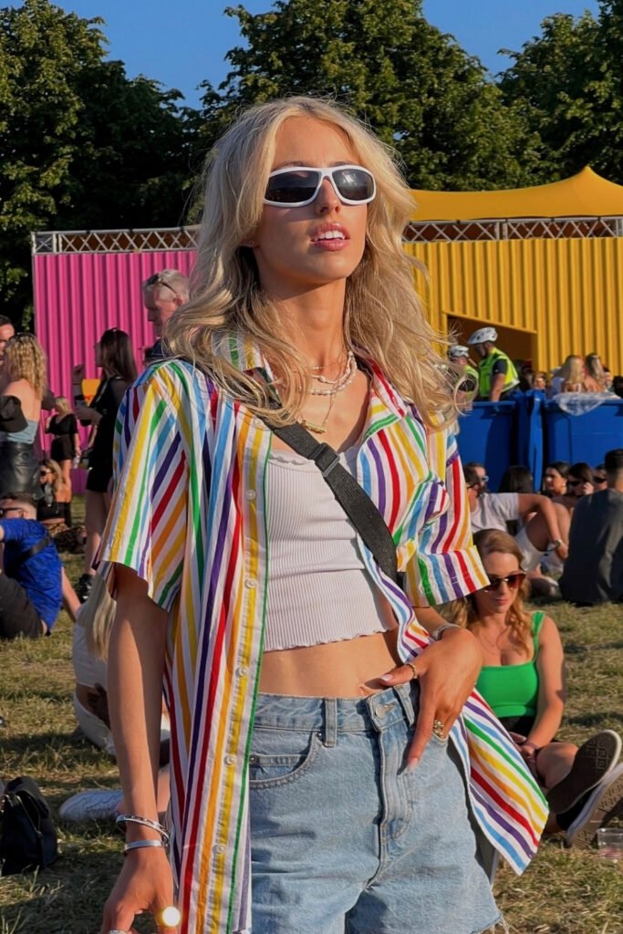 Rainbow striped shirt over a white crop top and jeans at a Pride festival