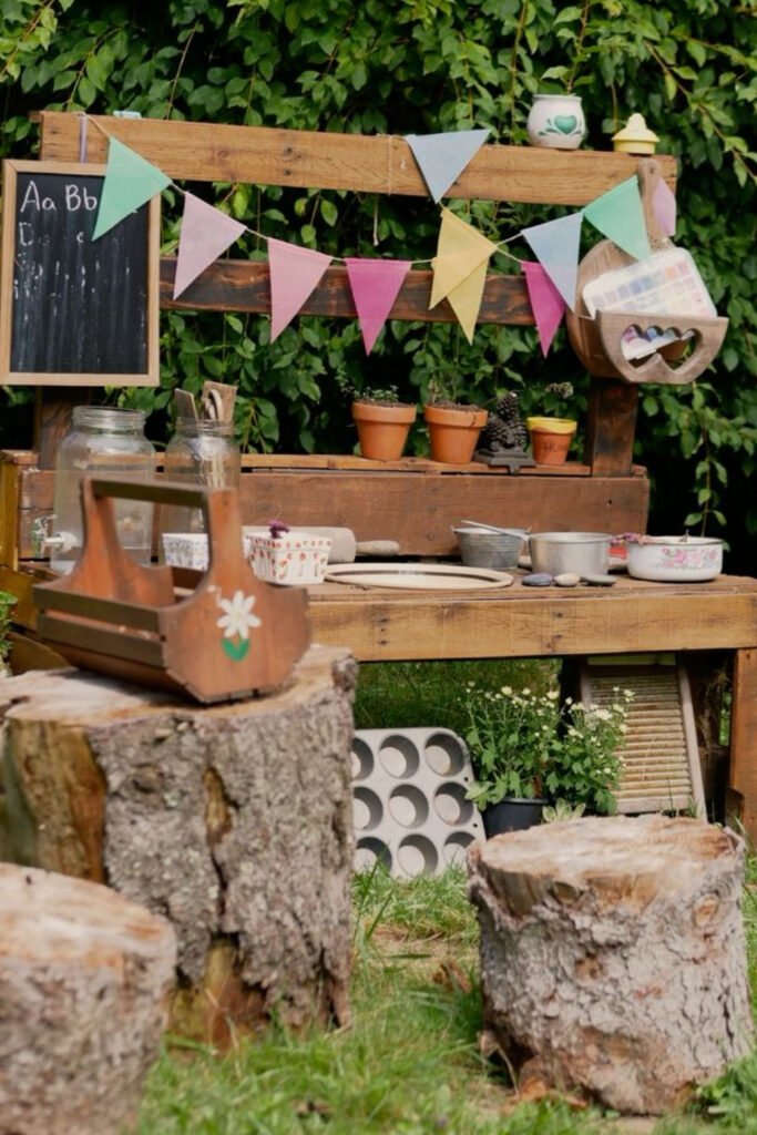 Mud kitchen with bunting and a chalkboard set on logs