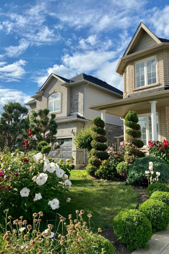 House with a front yard full of flower beds and shrubs along the walkway