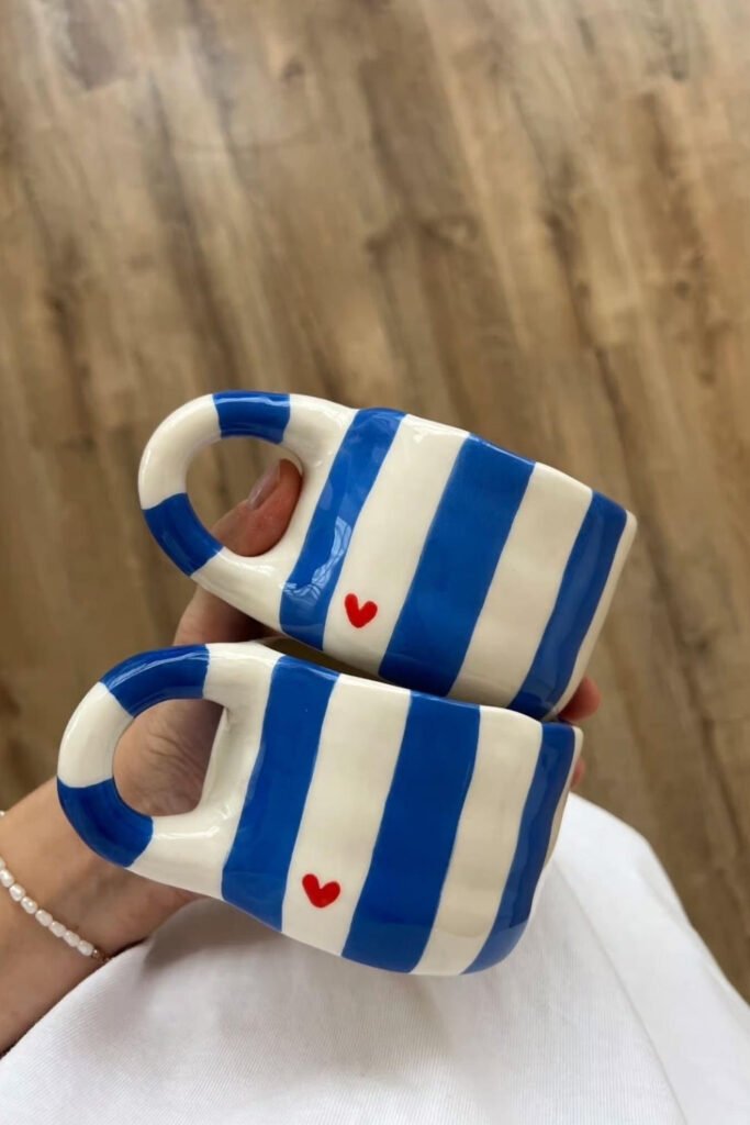 Two mugs painted with bold blue and white stripes