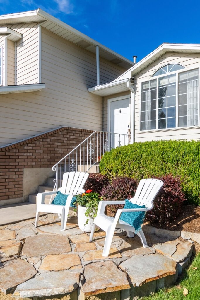 White house with a stone patio and two chairs in the front yard
