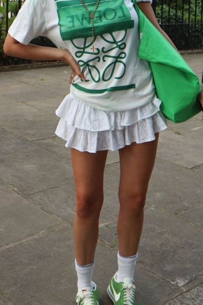 Green graphic tee with a white ruffle skirt and sneakers