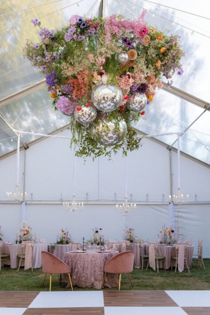 Hanging floral installation with mirror balls inside a white reception tent