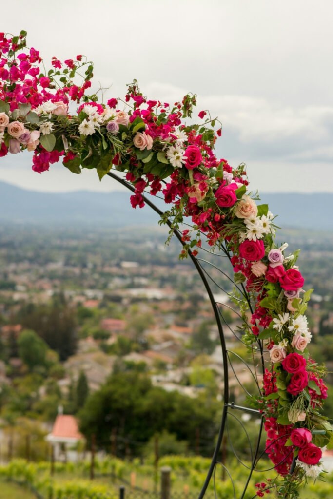 Wedding arch covered in pink and white flowers with a view of the valley