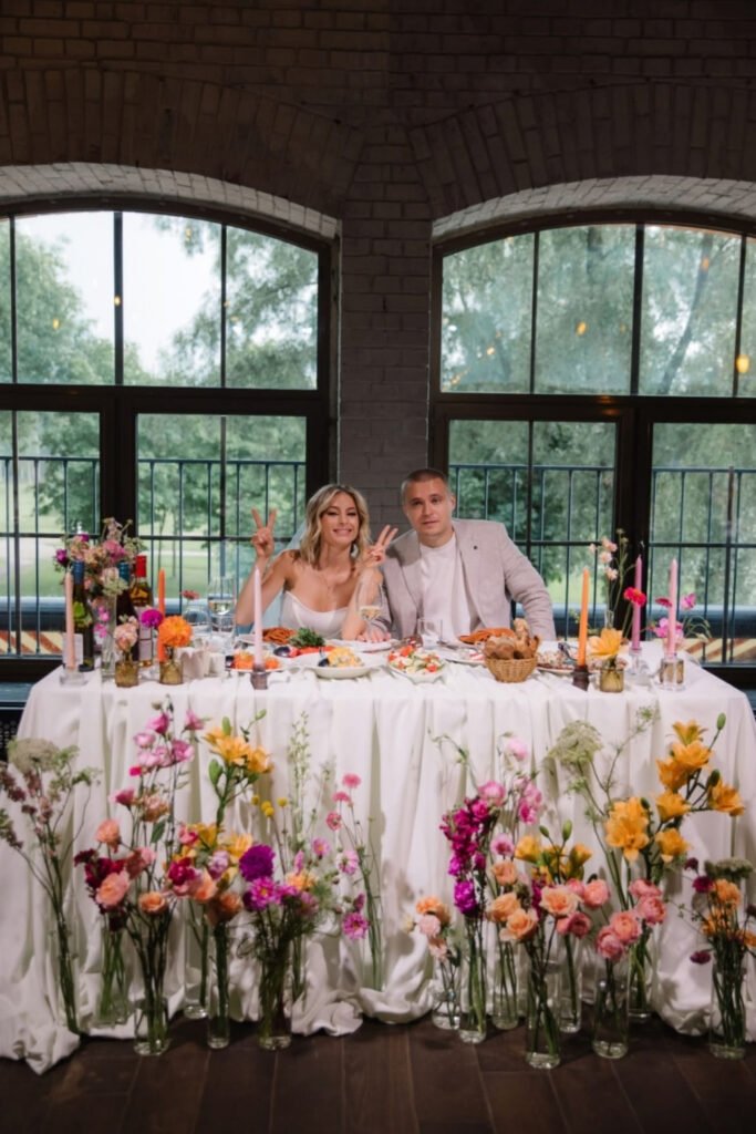 Head table covered in bright, overflowing wildflower arrangements