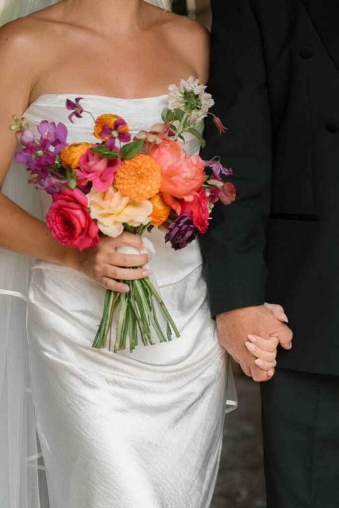 Bride holding a loose bouquet of pink and orange roses