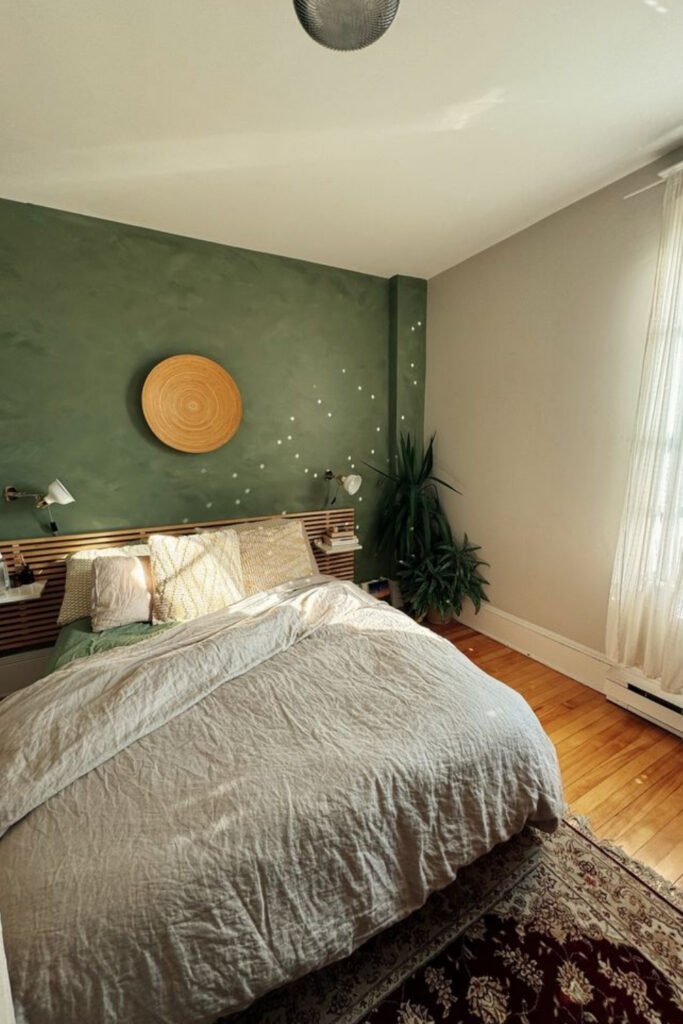 Bedroom with a muted green wall, wooden furniture and a round mirror