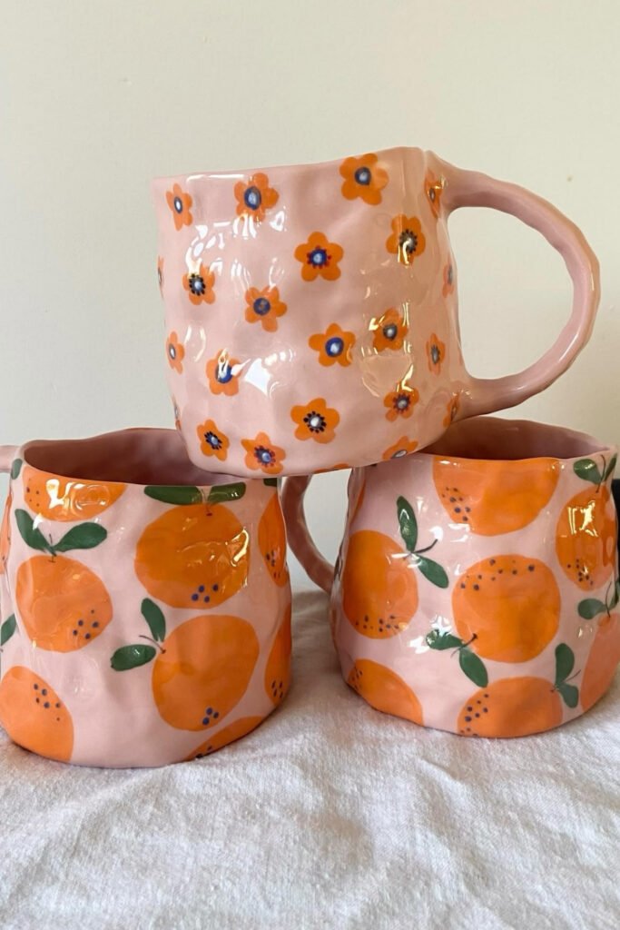 Pink mugs hand-painted with oranges and small flowers