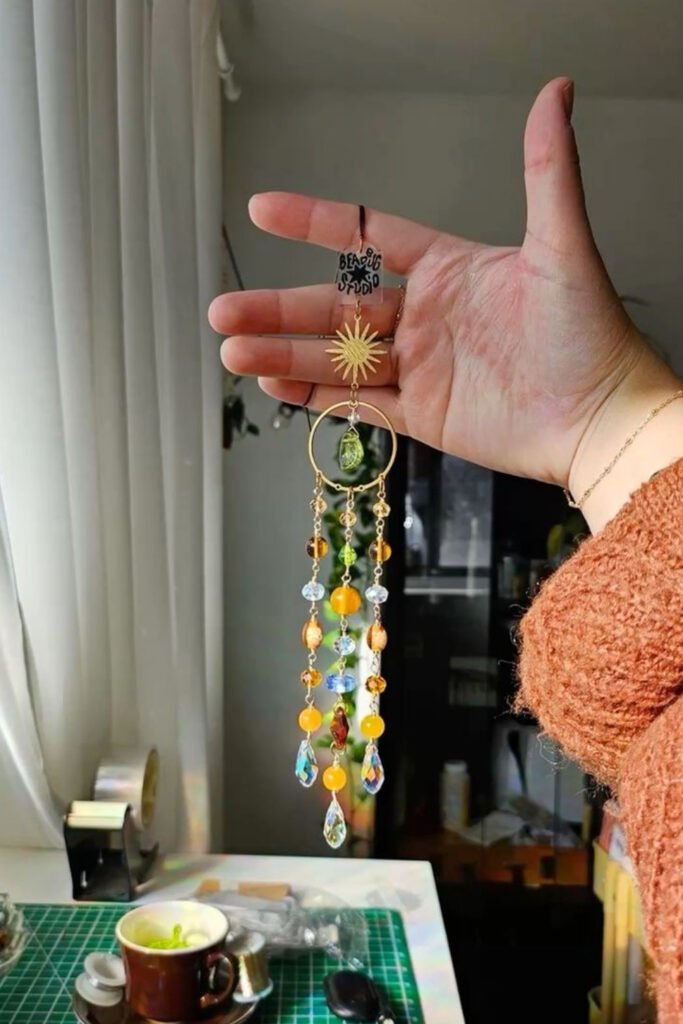 Hand holding a small homemade beaded wind chime with a metal charm