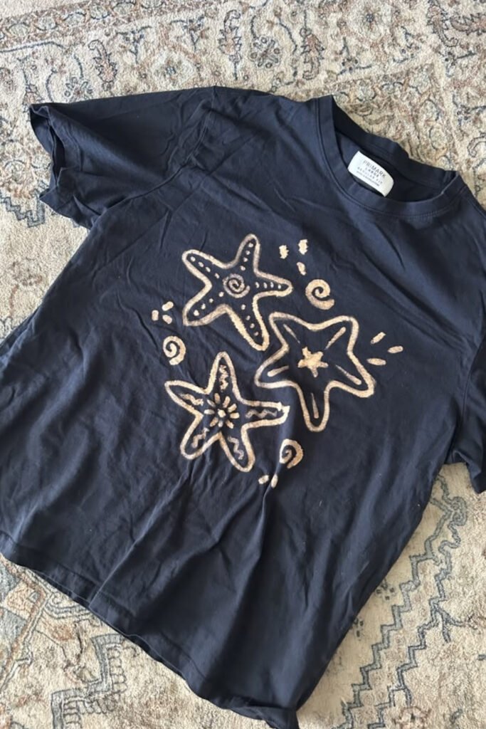 Black t-shirt with bleached starfish and seashell designs