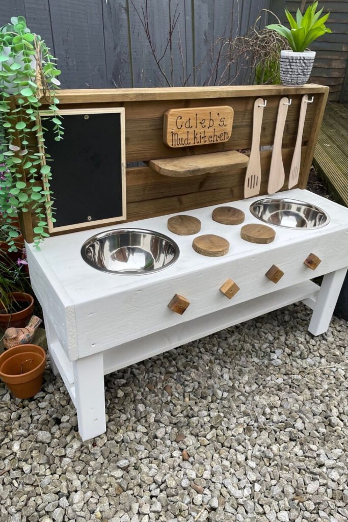White mud kitchen with bowls and a chalkboard