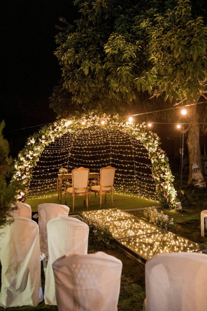 Dome of string lights over white chairs at an evening event