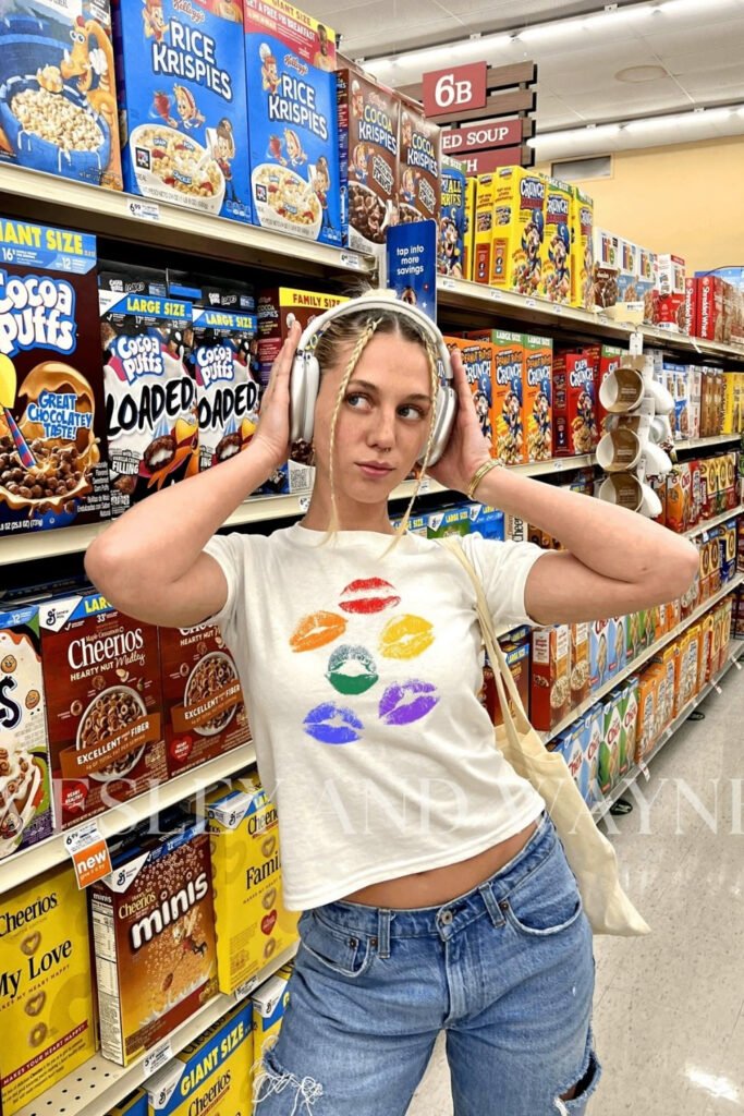 White graphic tee with rainbow hearts worn with jeans and headphones